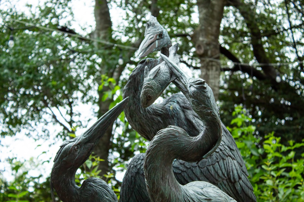 a statue of two birds in a forest