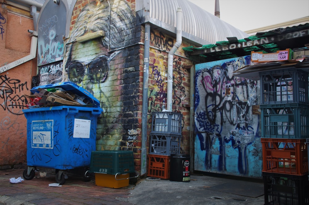 a trash can sitting next to a building covered in graffiti