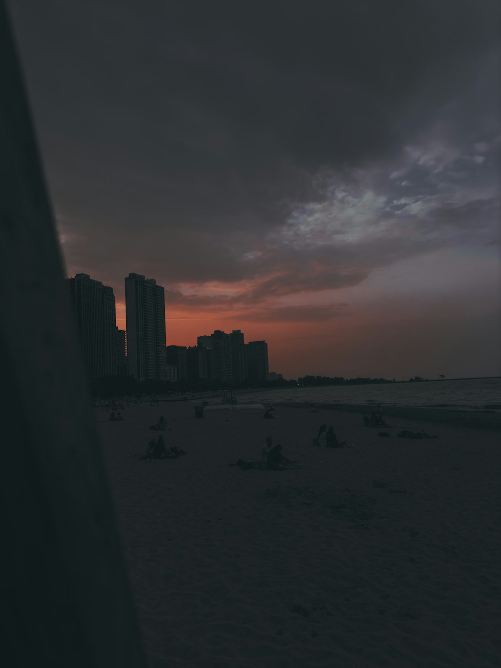 a view of a beach at sunset with buildings in the background