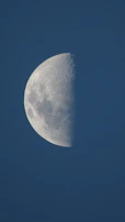 Close-up of a half-moon phase against a deep blue sky.