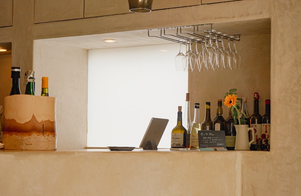 a counter with bottles of wine and a laptop on it
