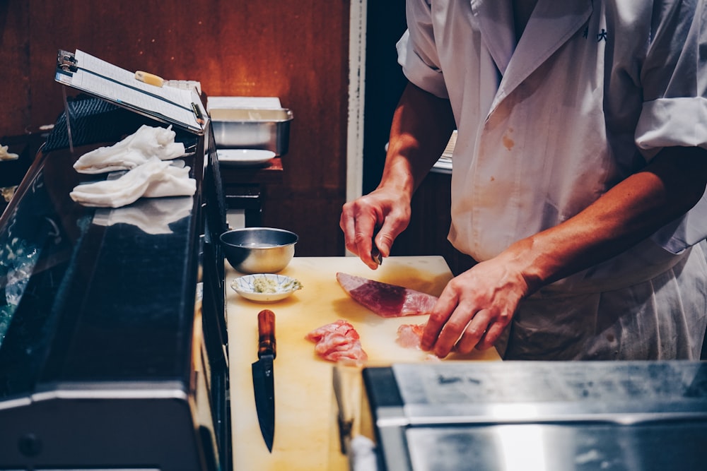 a man in a kitchen preparing food on a cutting board