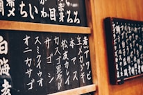 A friendly instructor explaining Japanese characters on a whiteboard with a warm smile.