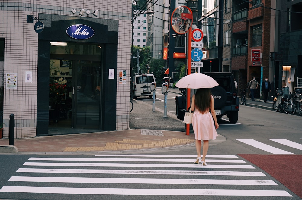 a woman walking across a street holding an umbrella