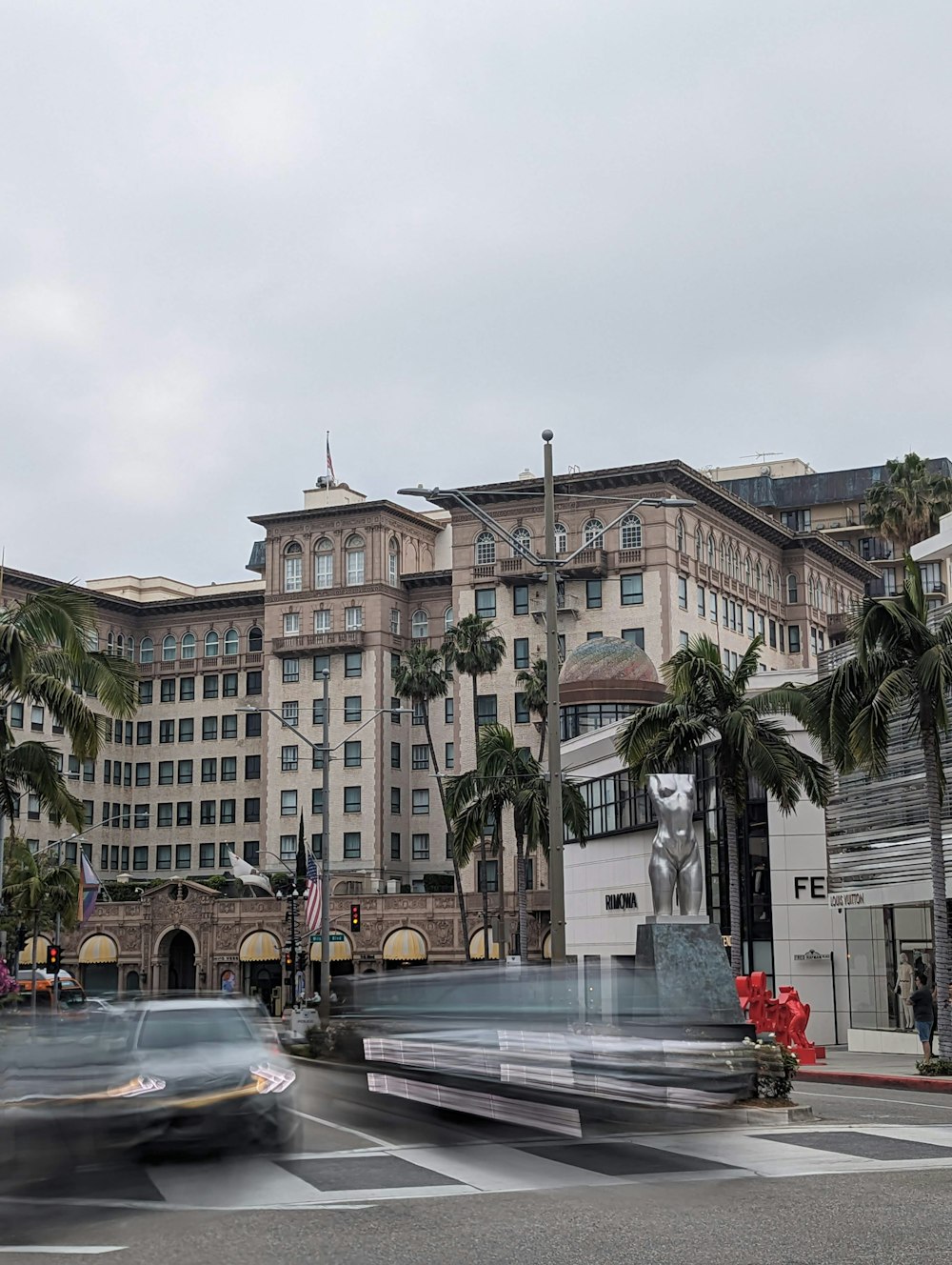 a car driving past a large building with palm trees