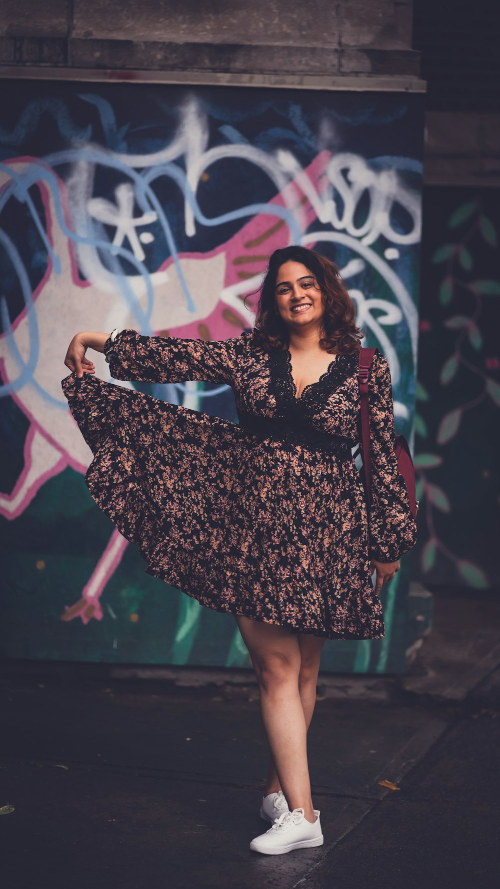 a woman standing in front of a graffiti covered wall