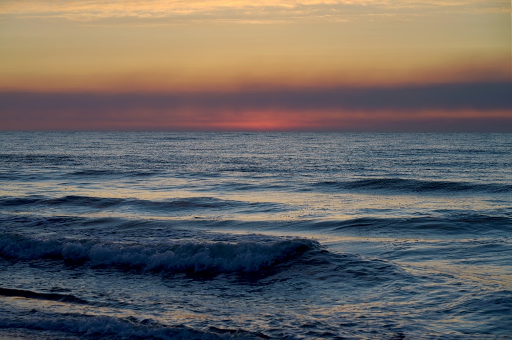 the sun is setting over the ocean waves