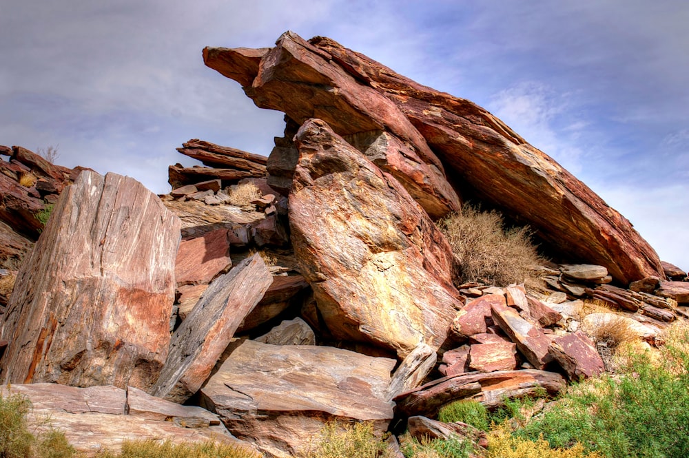 a pile of rocks sitting on top of a grass covered hillside