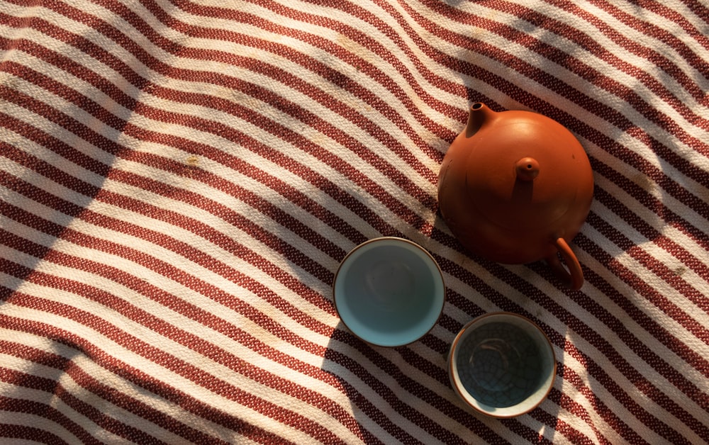 a teapot and two cups sitting on a blanket