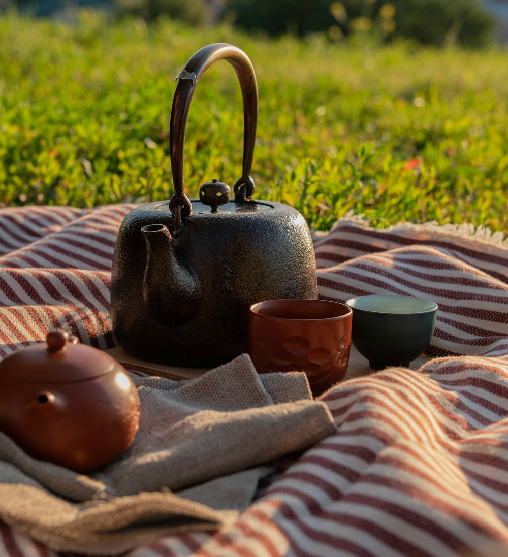 a tea pot and two cups on a blanket