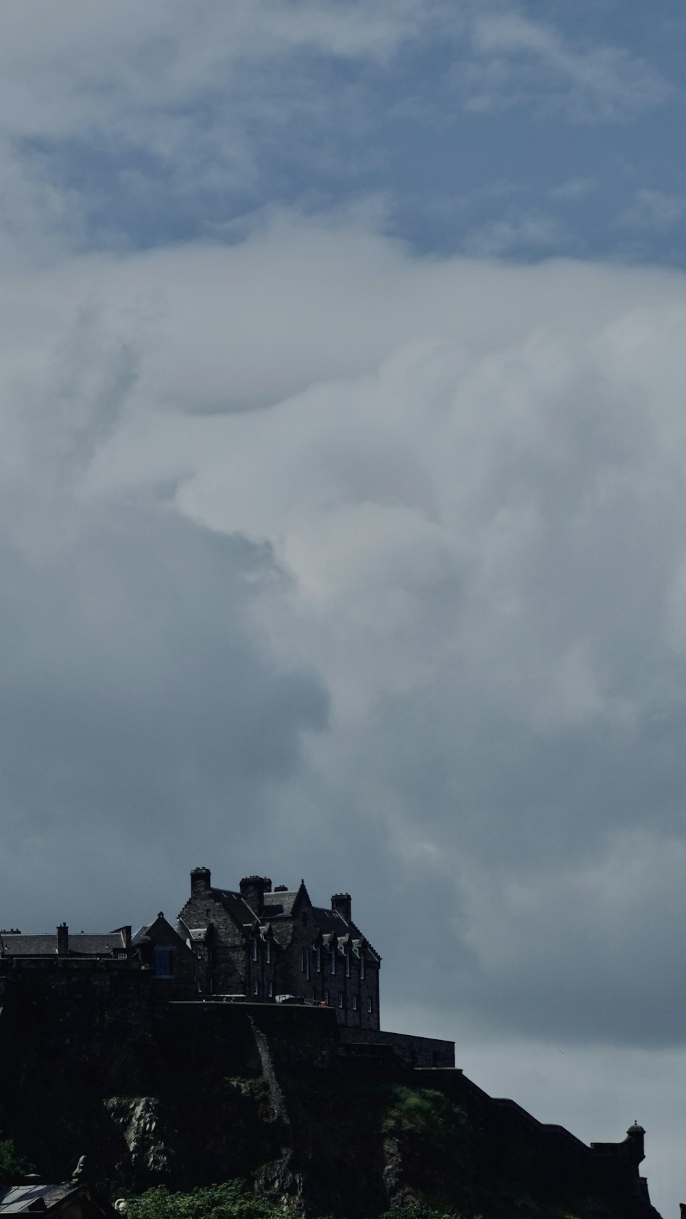 a castle on top of a hill under a cloudy sky