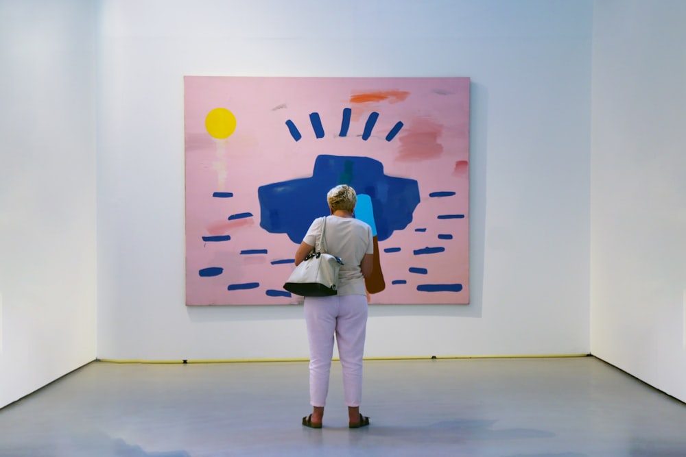 a woman standing in front of a painting