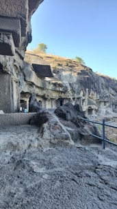 Scenic view of Ajanta caves with tourists exploring ancient rock-cut architecture.