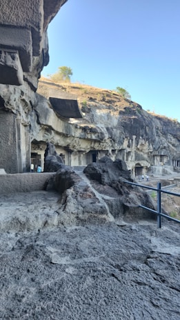The ancient Buddhist rock-cut caves nestled amidst rocky terrain under a clear blue sky.