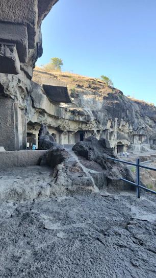 A scenic view of the ancient Ellora caves with a comfortable car parked nearby, ready for a journey.
