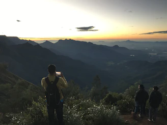 Sunset view of a backpacker checking their phone next to a scenic mountain trail.