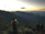 Photo of a man with a backpack using a smartphone on a mountain ridge.