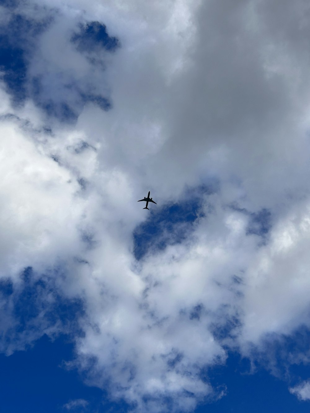 an airplane flying through a cloudy blue sky