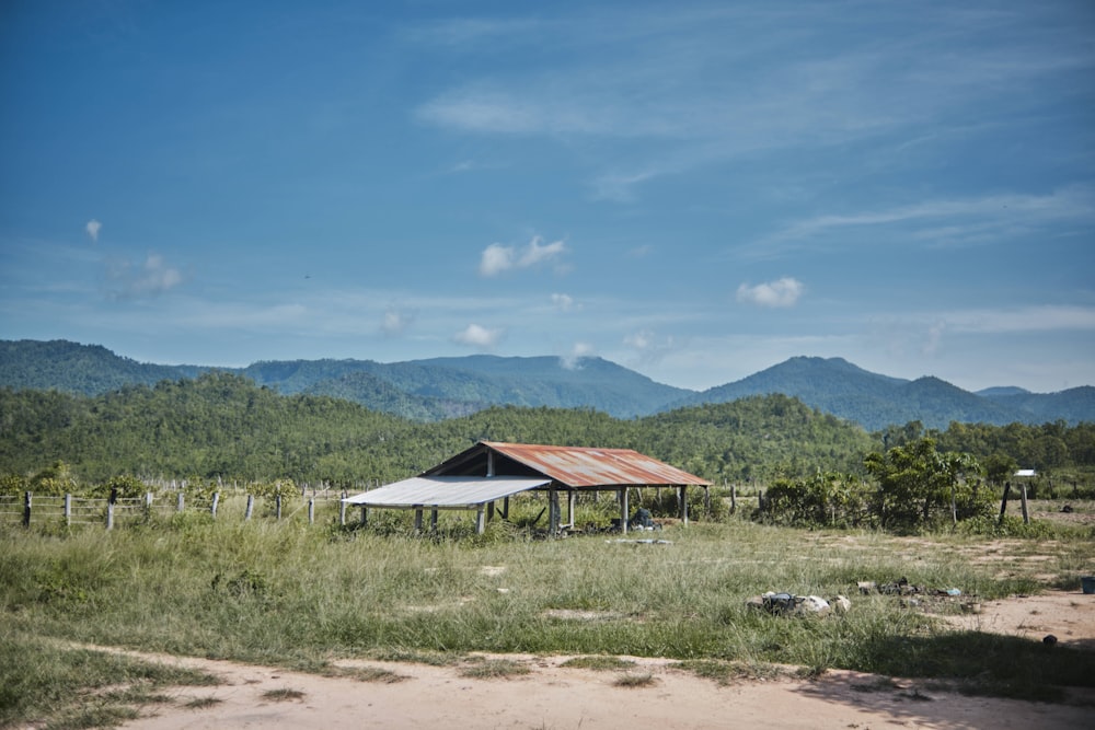 a barn in a field with mountains in the background