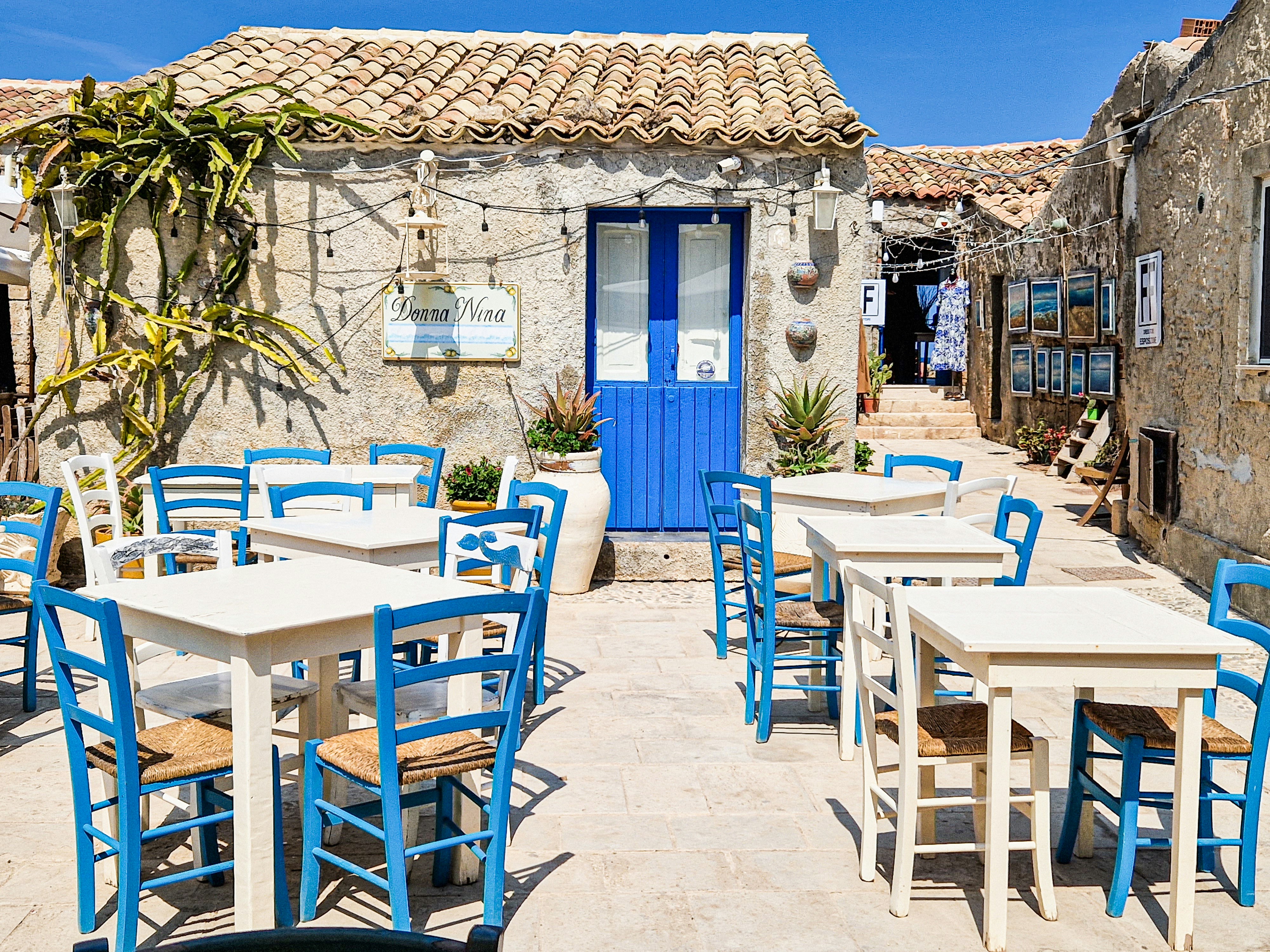 Tische und Stühle vor einem Restaurant mit blauer Tür