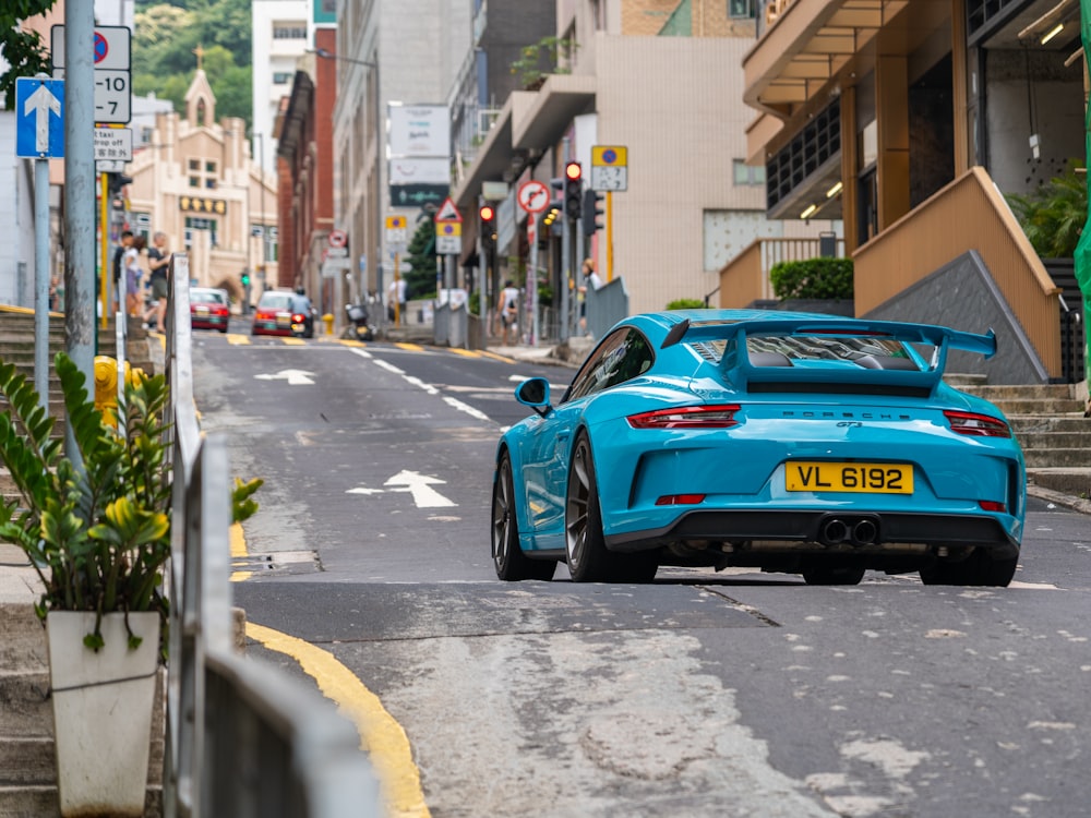 a blue sports car driving down a city street