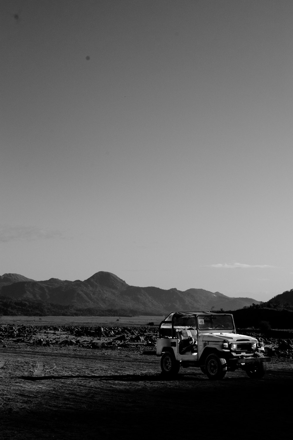 a black and white photo of a jeep in the desert