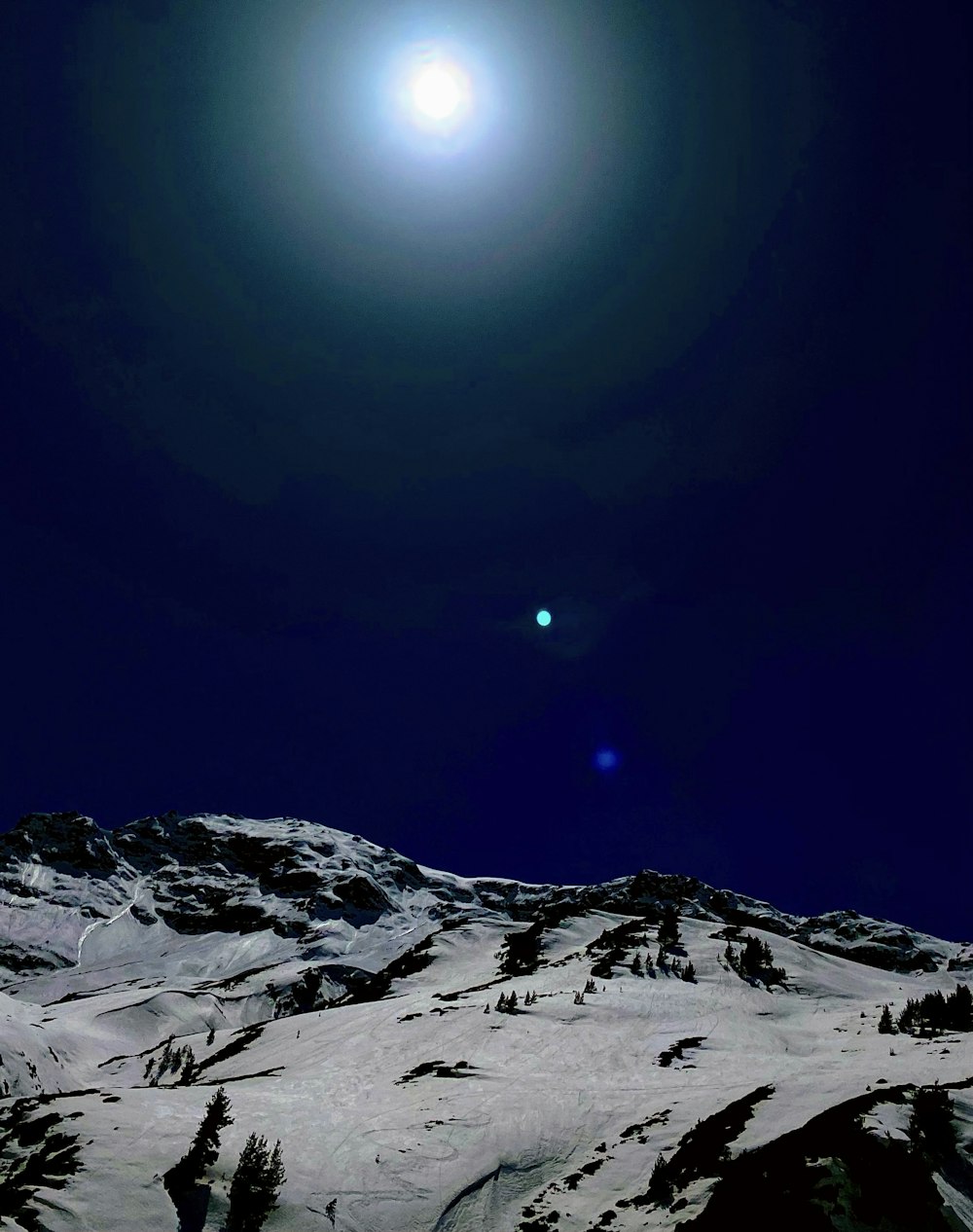 Ein Vollmond ist über einem schneebedeckten Berg zu sehen