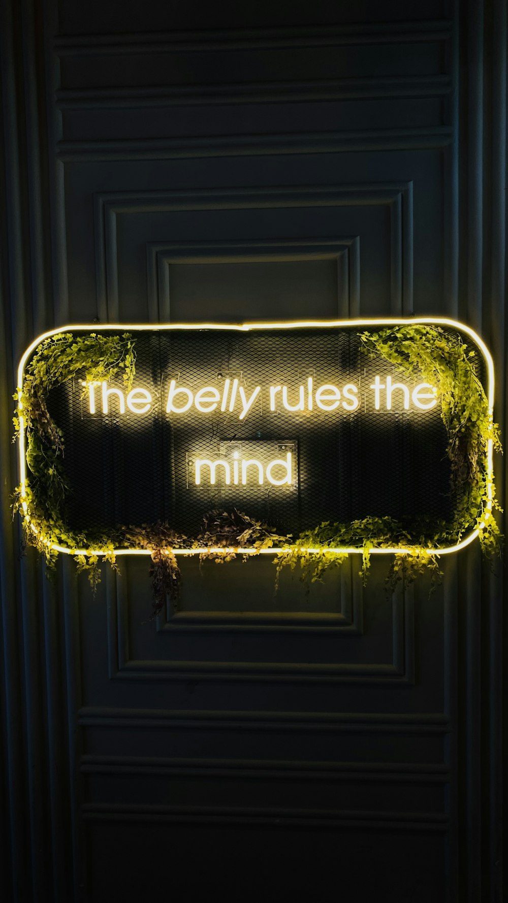 a neon sign that reads the belly rules the mind