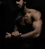 Side profile of a man wearing baggy pump covers, muscles tensed under low light.