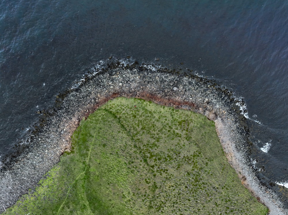 an aerial view of a grassy area next to the ocean