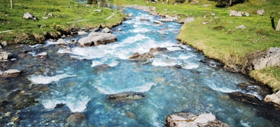 A clear mountain stream winding through natural landscape with charcoal rocks.