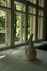 A sunny kitchen scene featuring hand-thrown stoneware pitchers with yellow and green glazes.
