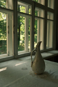 A sunny kitchen scene featuring hand-thrown stoneware pitchers with yellow and green glazes.