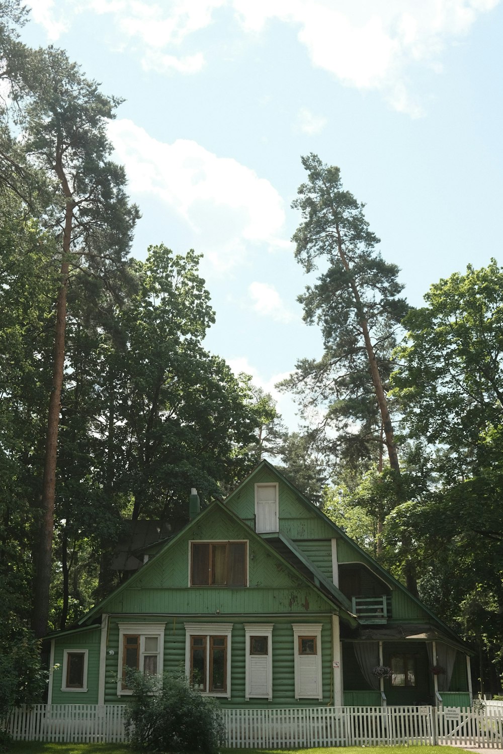 a green house with a white picket fence