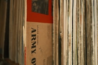 Close-up of vinyl records stacked on a dark surface with crimson reflections.