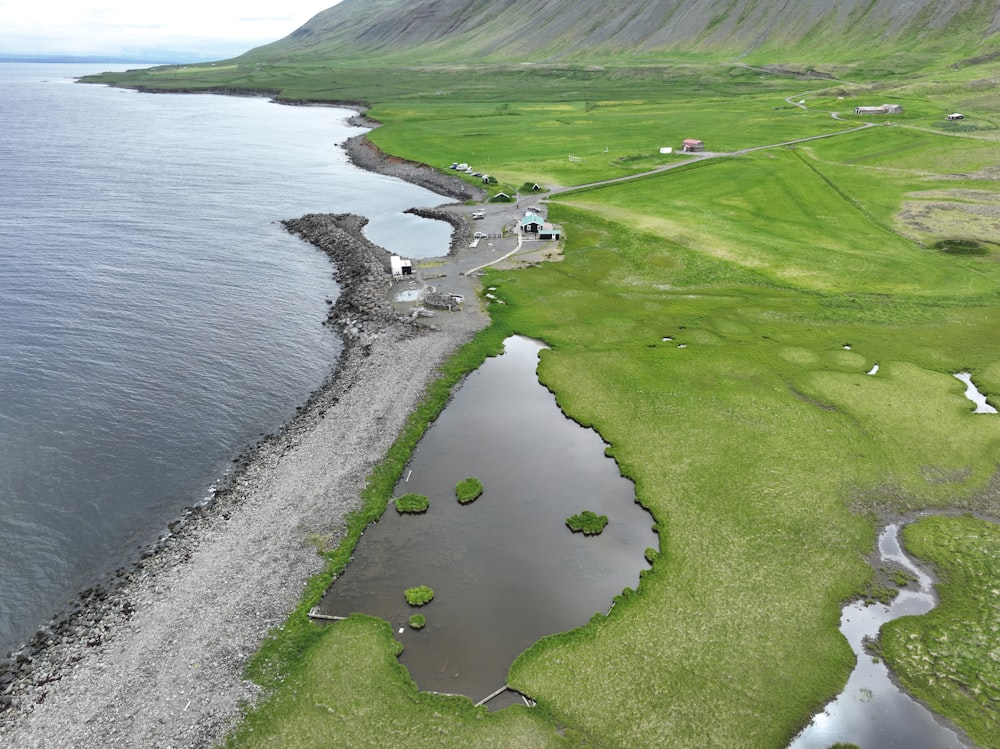 a large body of water next to a lush green hillside