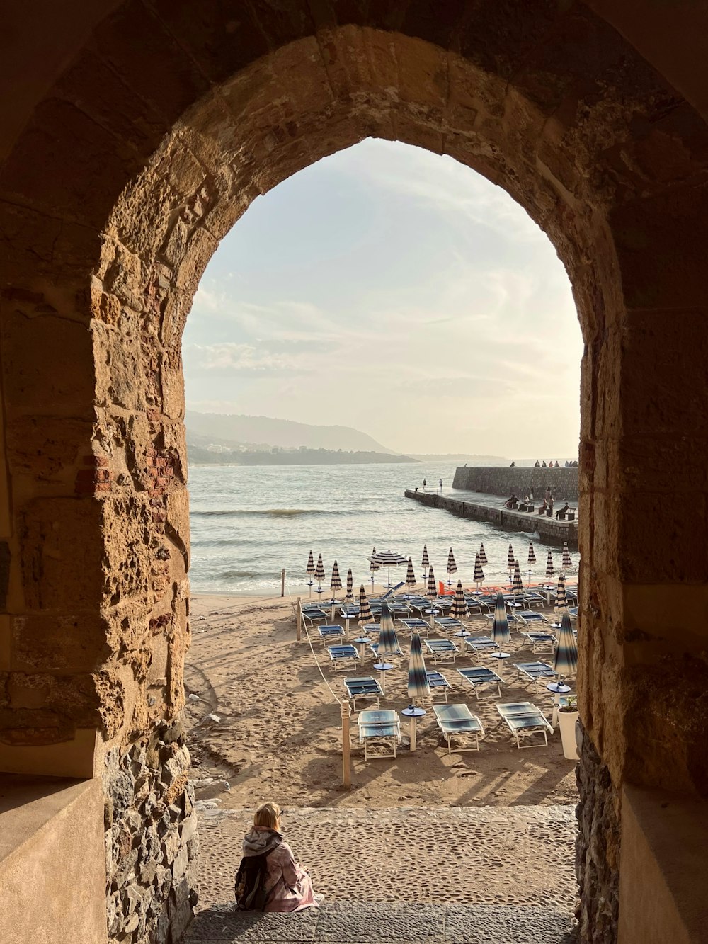 a person sitting on a beach under an archway