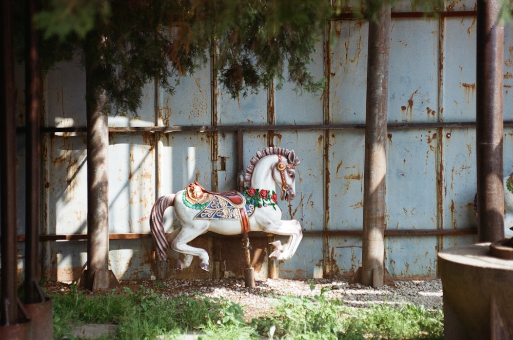 a white horse statue sitting on top of a lush green field