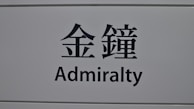 A sign featuring the word 'Admiralty' in English and corresponding Chinese characters on a light gray background.