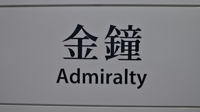 A sign featuring the word 'Admiralty' in English and corresponding Chinese characters on a light gray background.