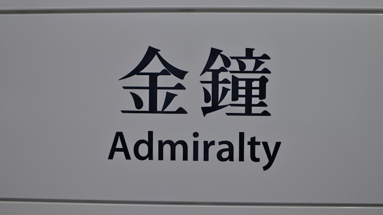 A sign featuring the word 'Admiralty' in English and corresponding Chinese characters on a light gray background.
