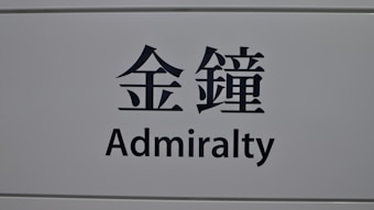 A sign featuring the word 'Admiralty' in English and corresponding Chinese characters on a light gray background.