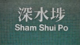 The image features a green tiled wall with white Chinese characters and the text 'Sham Shui Po' below.