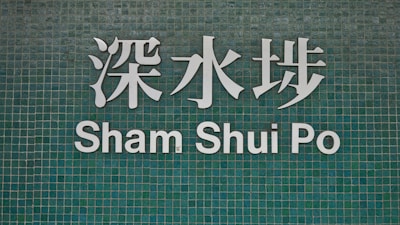 The image features a green tiled wall with white Chinese characters and the text 'Sham Shui Po' below.