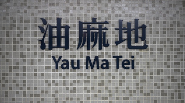Dark blue Chinese characters and the words 'Yau Ma Tei' in English are prominently displayed on a background of small, square grayish tiles.