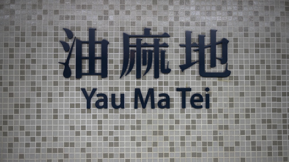 a tile wall with a sign that says yau ma tei