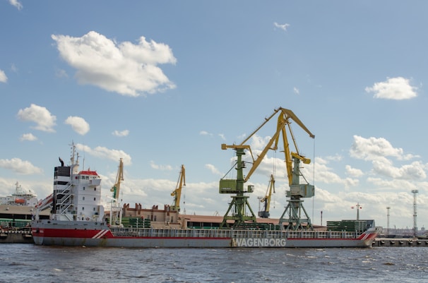 A sturdy cargo ship docked at a bustling Dutch port under a clear blue sky.
