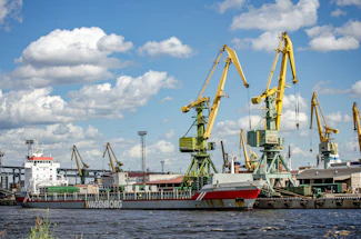A dockside ship unloader in action lifting bulk cargo under a cloudy sky.