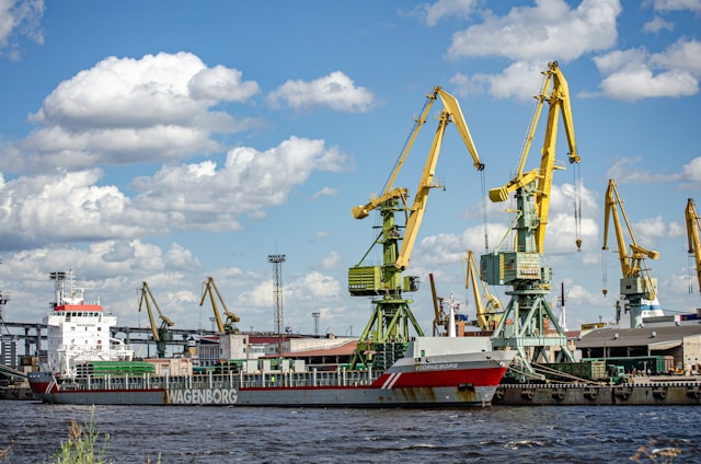 A busy cargo ship docked at a vibrant international port under a clear sky.