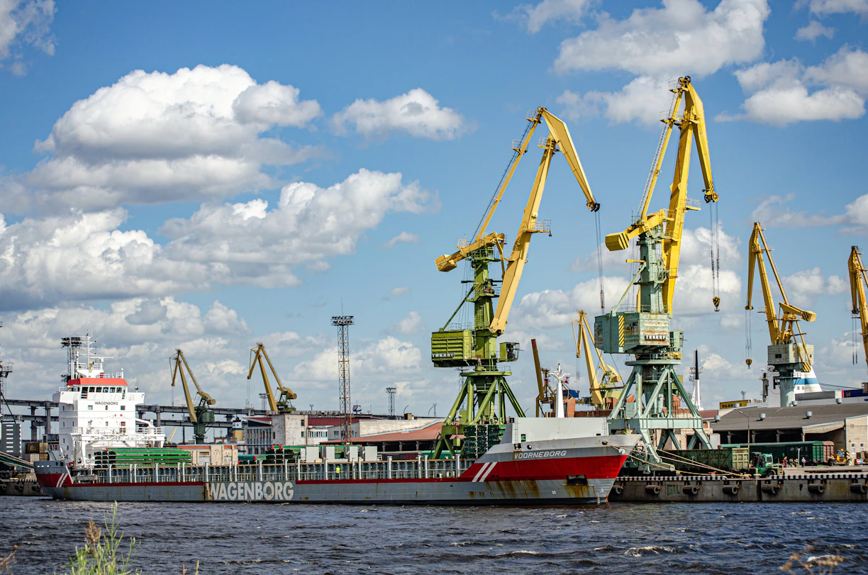 A busy cargo ship docked at Port Said with cranes unloading supplies under a clear sky.